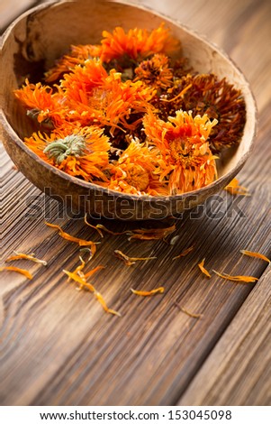 Homeopathic medicine, calendula dry flowers and wooden surface.