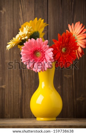Gerbera flower on the vase, and the wooden background.