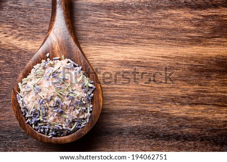 Sea salt wooden spoon on brown wooden background.