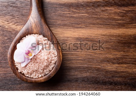Sea salt wooden spoon on brown wooden background.