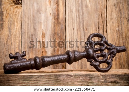 Old vintage key with heart on wooden background.