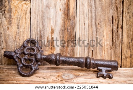 Old vintage key with heart on wooden background.