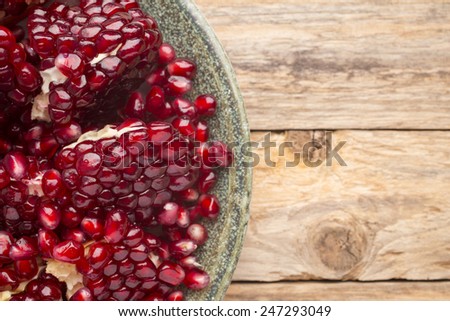 Pomegranate particles on a green plate and wooden table.