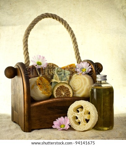 Composition of the basket full of handmade soap with bottle of oil and some flower decoration.