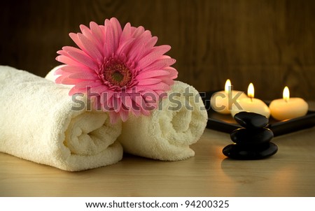 Towels and pink flower, candles and massage Stones in a Zen Spa.