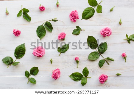 Pink roses with green leaves on wood background