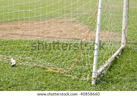 A shot of a soccer goal at the end of a empty field at a park.