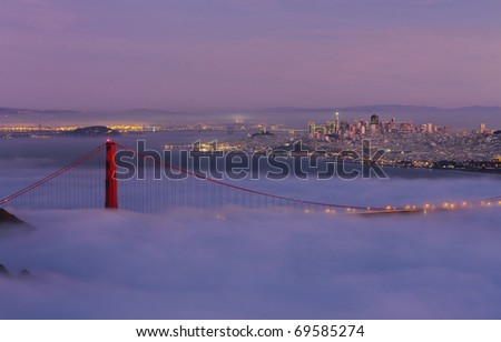 GOLDEN GATE NATIONAL RECREATION AREA, CALIFORNIA: Golden Gate Bridge taken from Hawk Hill overlook in Marin County with fog flowing over bridge at twilight.