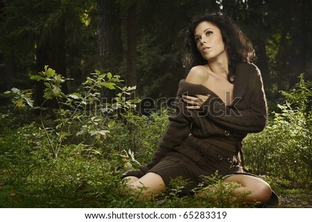 summer portrait of sexy girl sitting in a forest clearing among the green bushes and trees