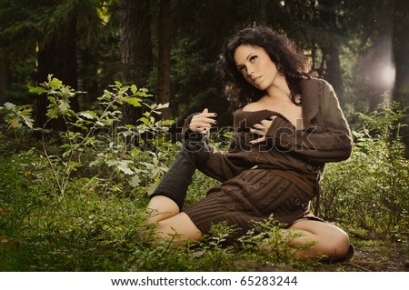 summer portrait of sexy girl sitting in a forest clearing among the green bushes and trees