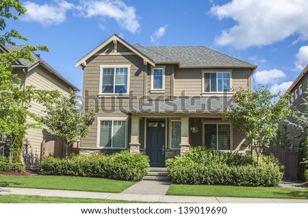 new luxury family house with landscaping on the front and blue sky on background and green grass on front