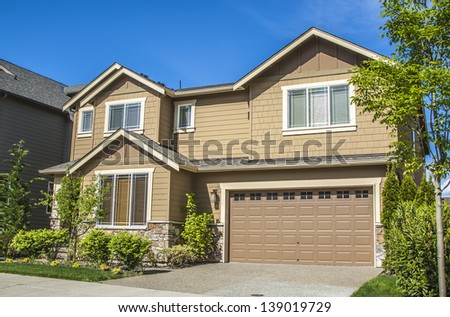 new luxury family house with landscaping on the front and blue sky on background and green grass on front