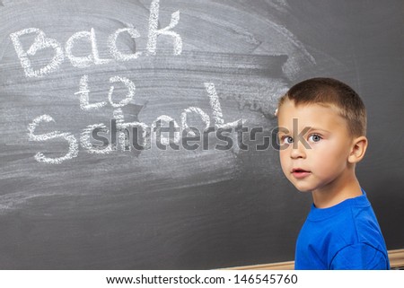 first grade student  writing  on chalkboard in classroom