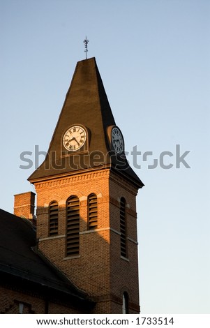 A newly repaired church clock tower catches the last hints of light from the sunset.