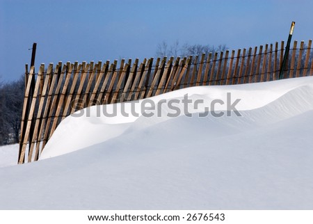 The winds and a snow fence have contrived to create a beautiful snow sculpture of drifts.  Full color.