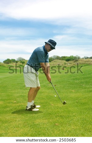 A man playing golf on the fairway. Golf club is in motion.