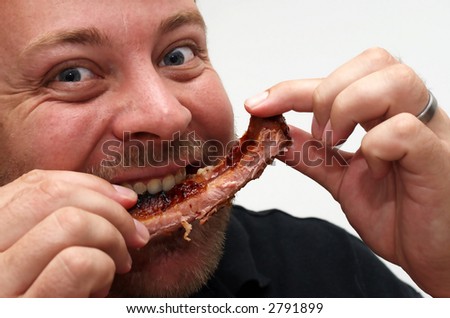Hungry blue-eyed man eating a rib with both hands. White background.