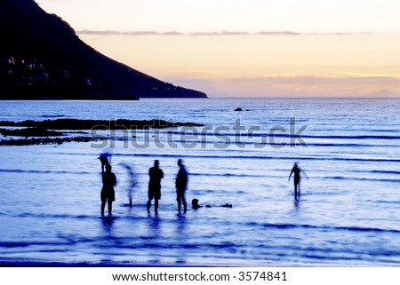 Silhouette of people in the water at sunset in Gordons Bay, South Africa