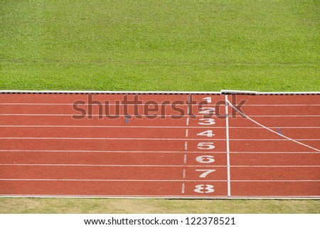 Start and finish line of red running track sports field.
