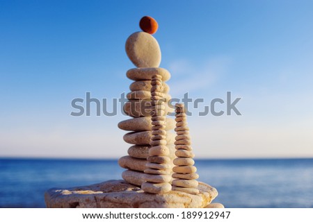 Balance of red stone on the top of stack of white pebbles