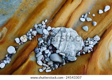 The sea pebble is thrown on a red stone in the summer morning