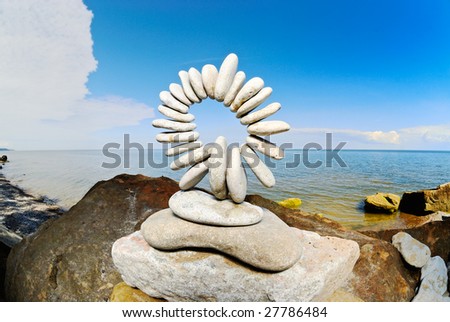 Sculptural sphere of pebbles on the sea cliff