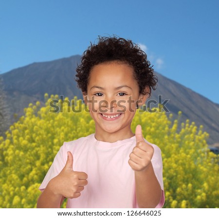 Happy latin child saying Ok with a volcano and a tree of background