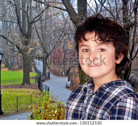 Smiling child with plaid t-shirt in a park during autumn