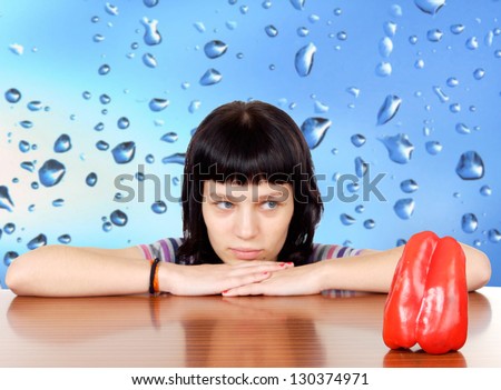 Pensive girl looking a red pepper with a wet blue background (focus in the pepper)