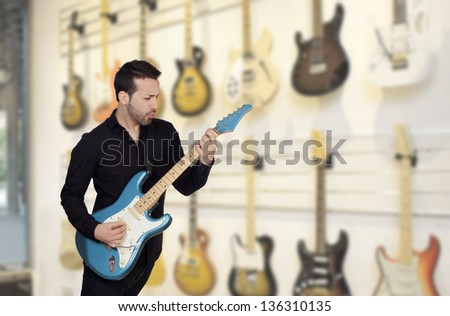 Attractive men playing a electric guitar in a music store