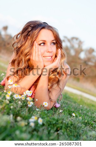 Pretty cool woman lying on the grass surrounded by flowers
