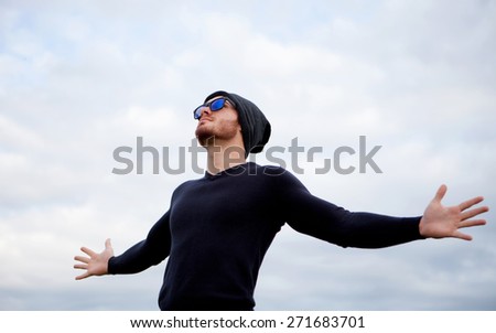 Cool handsome guy with his arms extended with the sky of background