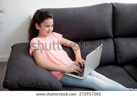 Little girl in the sofa at home with a laptop