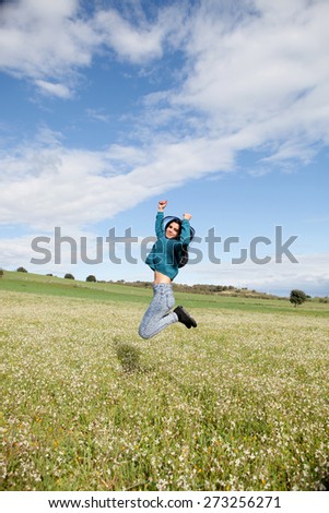 Young brunette girl jumping in a field full of flowers