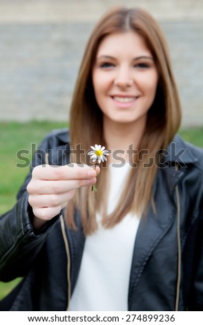 Pretty cool girl offering a beautiful flower. Focus in the daisy