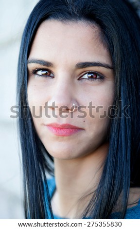 Brunette girl with a piercing in her nose looking at camera