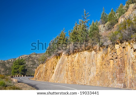 mountain road with sharp curve with blue sky background