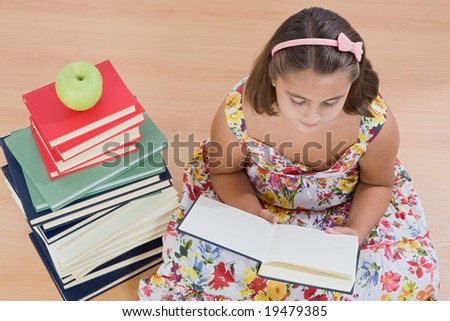 Adorable girl reading with many books reading on wooden floor view from above