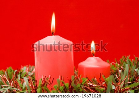 Red candles of Christmas lit on a over red background
