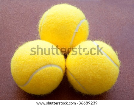 three tennis balls together in yellow on brown background