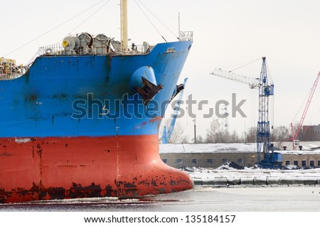 cargo ship's bow heading forward against port cranes