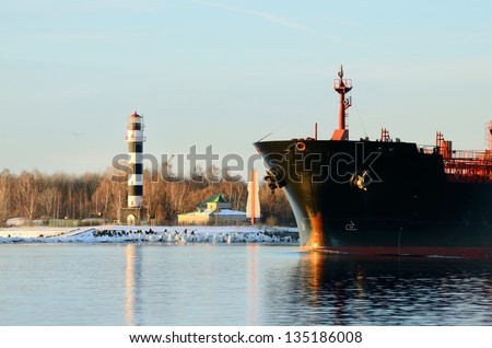 cargo ship\'s bow heading forward against a lighthouse