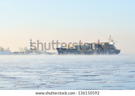 cargo container ship sailing in still frozen winter sea