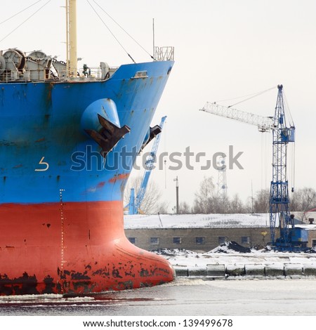 cargo ship\'s bow heading forward against port cranes