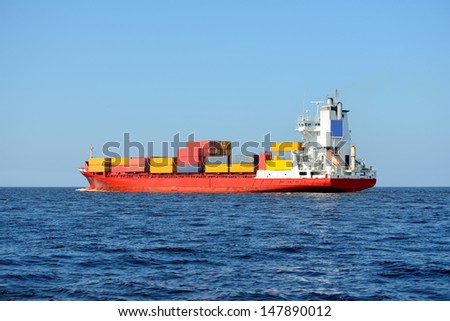 red container ship loaded with colorful cargo containers at the sea