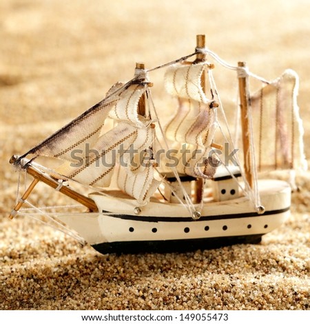 wooden sail ship toy model in the sea sand close-up