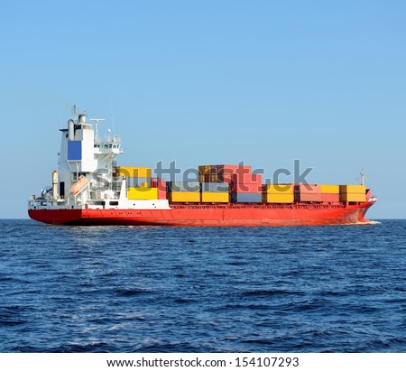 red container ship loaded with colorful cargo containers at the sea