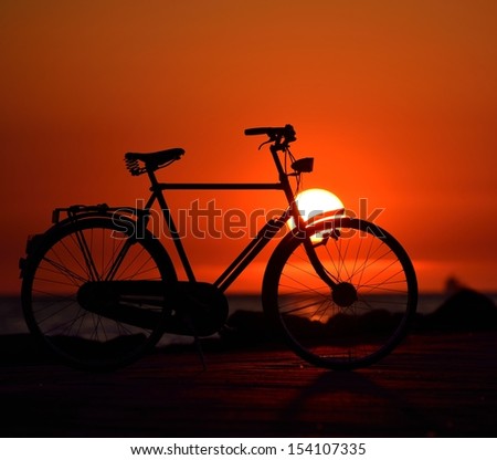 Old dutch retro bicycle on the beach against red sunset