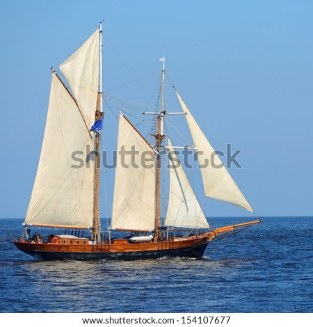 old historical tall ship (yacht) with white sails in blue sea