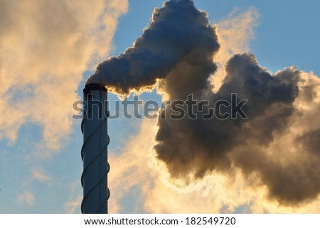 Factory pipe close-up with a lot of smoke against blue sky